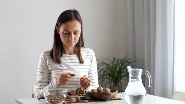 Young Woman is Cracking a Walnuts at Domestic Room