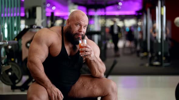 Bodybuilder with Big Muscles Drinking Fresh Orange Juice Balanced Fitness Nutrition Workout alt