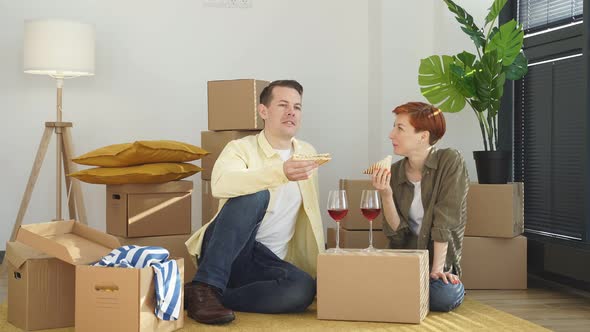 Positive Man And Woman Eat Sandwich Drinking Red Wine Celebrating Relocation And Moving Into New