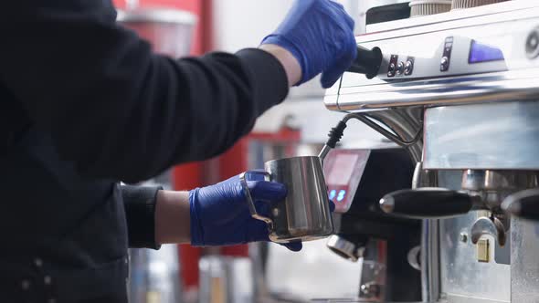 Unrecognizable Male Barista Cleaning Steam Wand After Steaming Milk in Coffee Machine Indoors alt