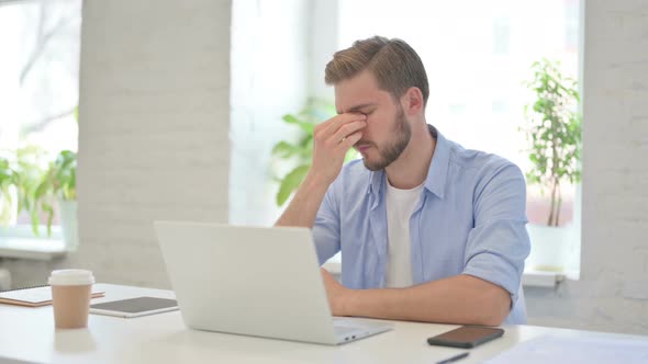 Young Creative Man with Laptop Having Headache alt