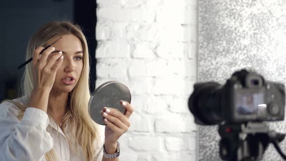The Beauty Vlogger Is Painting Her Eyebrows on Camera with a Mirror alt