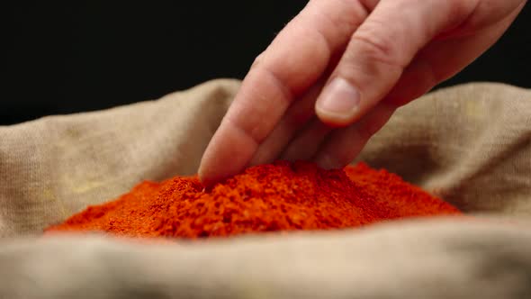 Human hand touching a red pepper powder in a sac