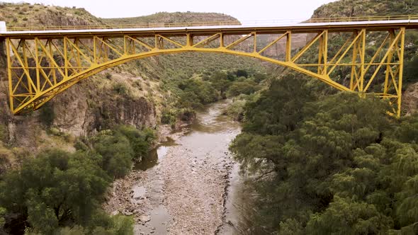 Drone video of a bridge on the highway and below a river between the mountains surrounded by trees i alt