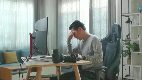 Asian Cameraman Being Tired While Using Desktop Computer For Working At Home alt