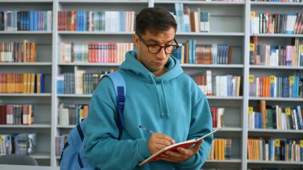 Closeup Portrait of a Young Attractive Student Guy Against the Background of Bookshelves in the