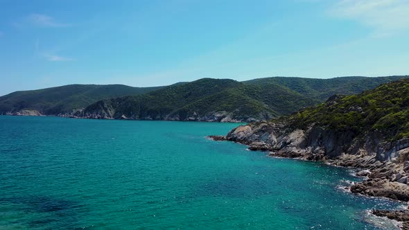 Hidden beach discovered behind rocky coastline and crystal clear blue sea in the Mediterranean aeria alt