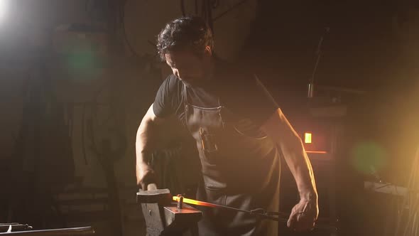 Blacksmith Works in a Workshop with a Preform of Molten Metal. Slow Motion