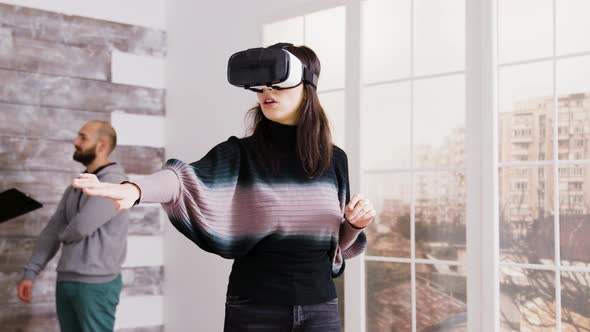 Female Architect Using Virtual Reality Goggles in Empty Apartment alt