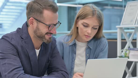 Male and Female Colleague Working on Laptop Together alt