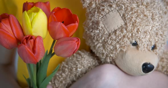 Hold teddy bear and flowers.  alt