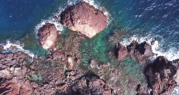 Aerial top view of waves break on rocks in a blue ocean. Sea waves on beautiful beach aerial view alt