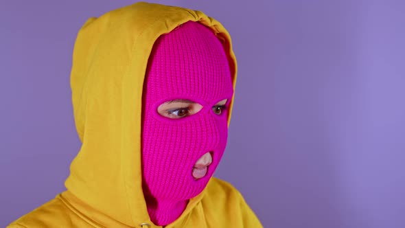 Close Up of Young Woman in Pink Balaclava and Yellow Hood Pondering About Her Life on Purple alt