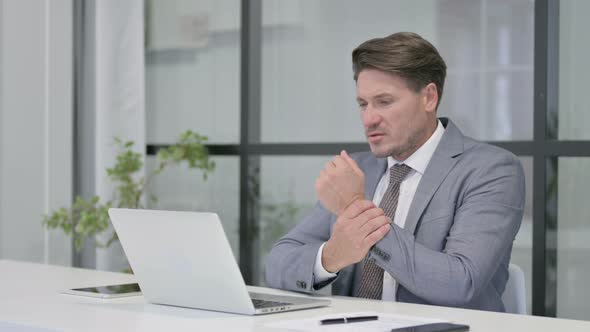 Middle Aged Man having Wrist Pain while using on Laptop alt