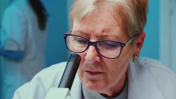Close Up of Senior Scientist Making Research Using Microscope alt