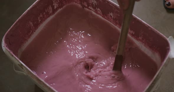 Close up view of potter mixing paint in a container at pottery studio alt