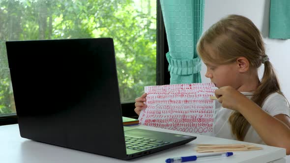 Child Girl Does School Homework Using Laptop Computer at Home