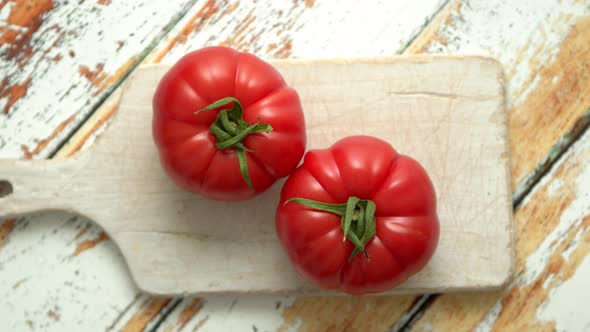 Top View of a White Cutting Board with a Fresh Juicy Tomatoes on a Wooden Table alt