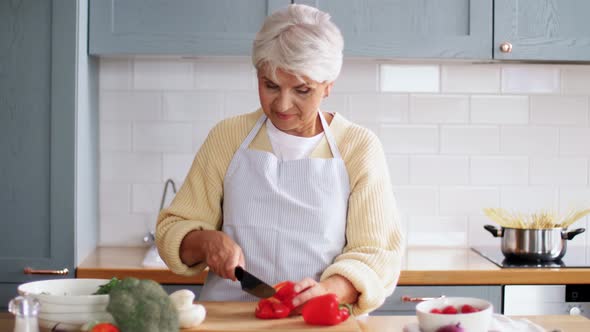 Happy Woman with Knife Chopping Pepper on Kitchen