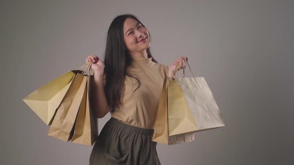 Confident asian woman happy holding shopping bag dancing smilling and looking at camera