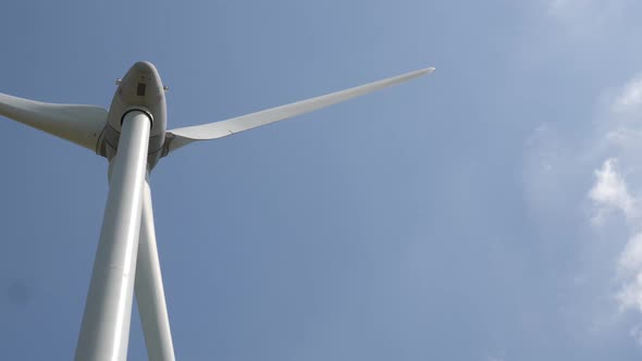 Wind turbine in operation against a background of blue sunny sky. the silhouette of the wind turbine