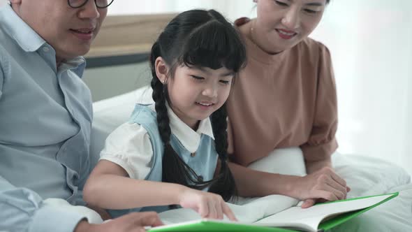 Father and mother are teaching their daughter homework at home, cosy family and education concept alt