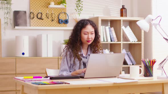 Energetic Asian businesswoman working on laptop from home office. Using computer remote studying, br alt