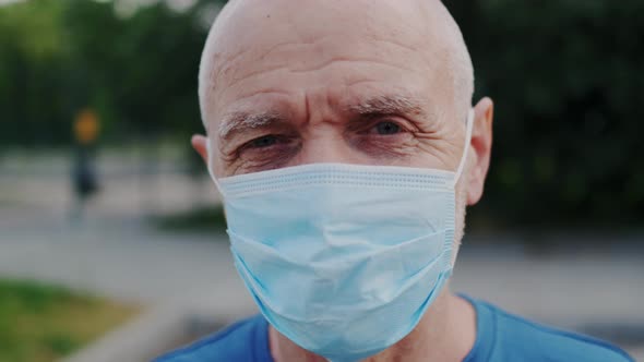 Close Up Portrait of Handsome Old Male Doctor Wearing Medical Face Mask Outdoors alt