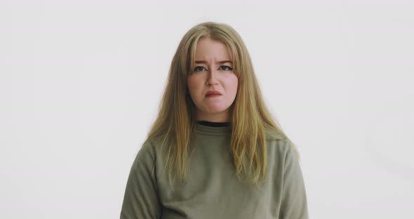 Upset Woman in Green Touches Neck Posing for Studio Camera alt