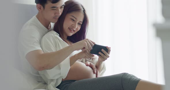 Caucasian husband with a pregnant wife looking ultrasound photo of her newborn baby.