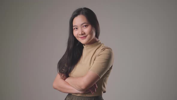 Confident asian woman happy standing smilling and looking at camera standing over background.