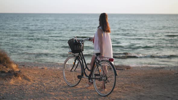 Young Carefree Happy Woman with Bicycle Looking Away Smiling Standing on Yellow Beach at alt