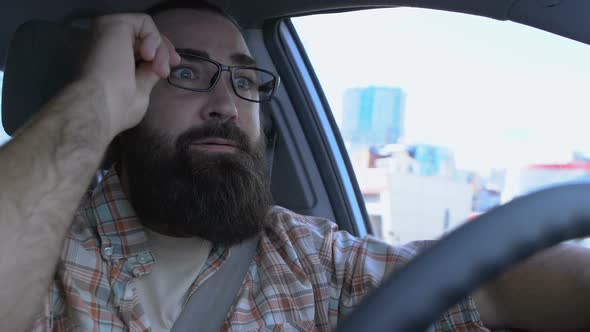 Car Driver Having Poor Vision, Taking Off Glasses and Squinting to See Road Sign