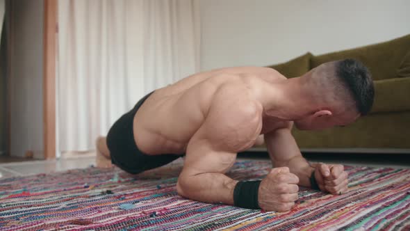 A Young Bodybuilder Training in His Room on a Mat and Makes an Original Plank Pumping the Muscles of alt
