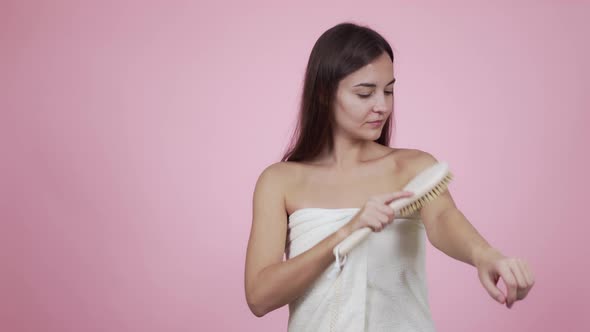 Portrait of Woman Doing Body Massage with Brush Isolated on Pink Background alt