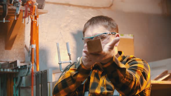 Carpentry Indoors - a Man Woodworker Inspect Cuted Detail for the Imperfections alt