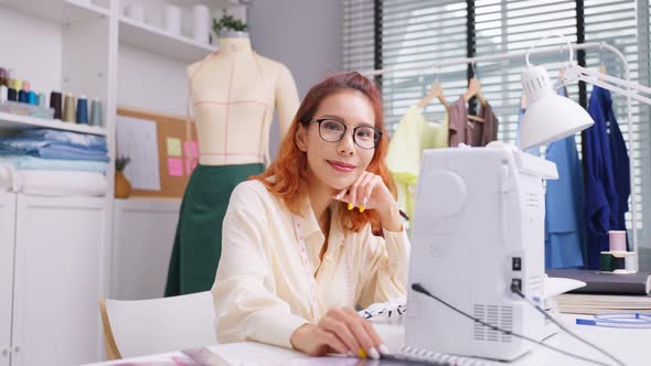 Portrait of Asian tailor woman look at camera after success in make new clothes in tailoring atelier alt
