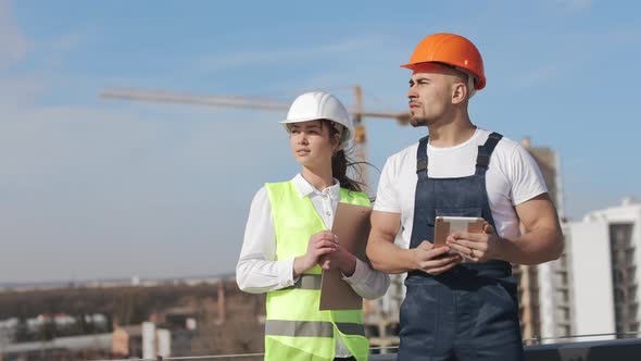 Two Serious Engineers are Standing and Looking Away alt