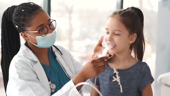 African Woman Doctor Holds a Mask Vapor Inhaler for Little Girl alt