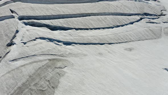 Aerial view over cracks on a icy glacier surface, in sunny Iceland - tilt, drone shot alt