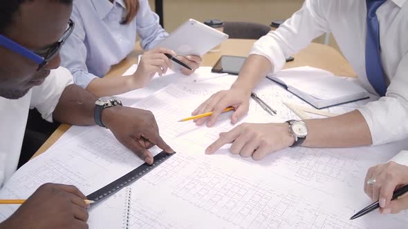 Multi Race Team of Architects and Engineers Rewieving Project Blueprint in Modern Office alt