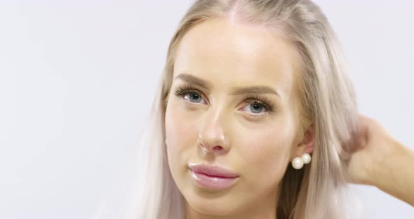Close-up Portrait of a Smiling Young Woman Touching Her Blonde Hair