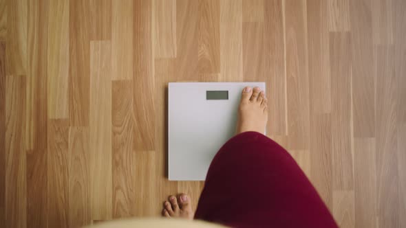 Legs of losing weight woman stand on scales and numbers, her weight, and top view shown on scales alt