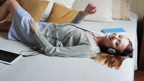Woman Lying on Bed Listening to Music alt