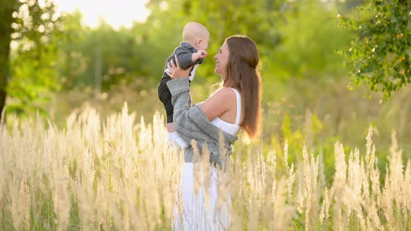 Happy young mum and baby walking together outdoor enjoy beautiful field of sunshine and spring