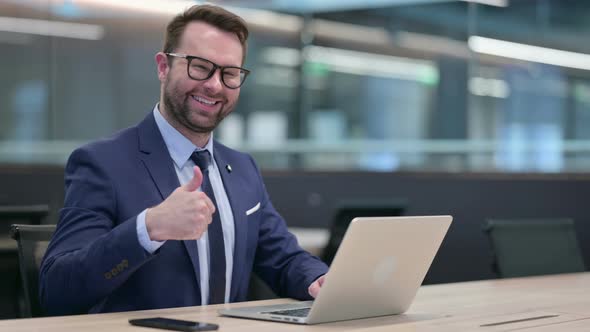 Middle Aged Businessman Using Laptop with Thumbs Up Sign alt