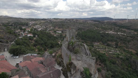 Fly over ruins of Sortelha hilltop castle, Portugal. National flag waving