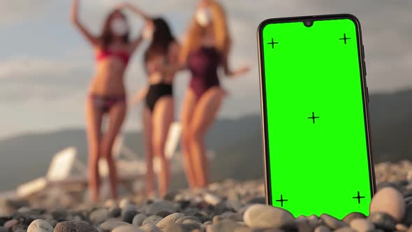 Phone with a Green Screen and Tracking Dots on the Beach Three Multiracial Girls in Swimsuits
