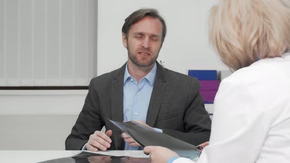 Mature Man with Joint Pain Talking To His Doctor After X-ray Scanning