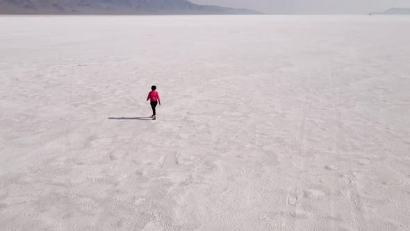Aerial shot of an Asian woman hiking across the Bonneville Salt Flats flats alt